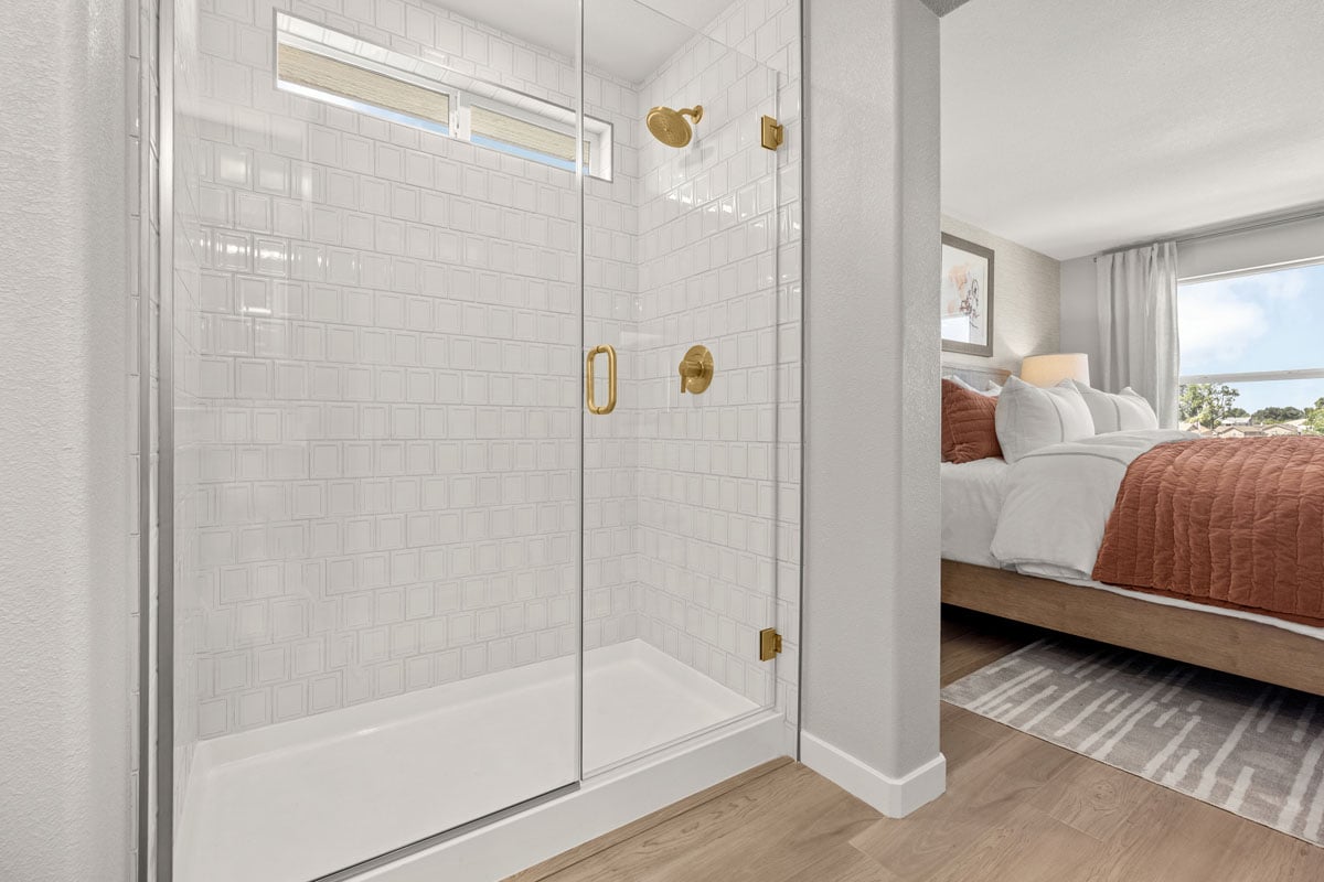 Walk-in shower with frameless clear glass enclosure at primary bath