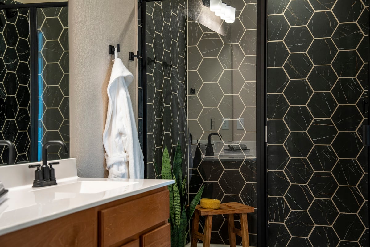  Walk-in shower with hexagon tile surround and matte black enclosure at primary bath